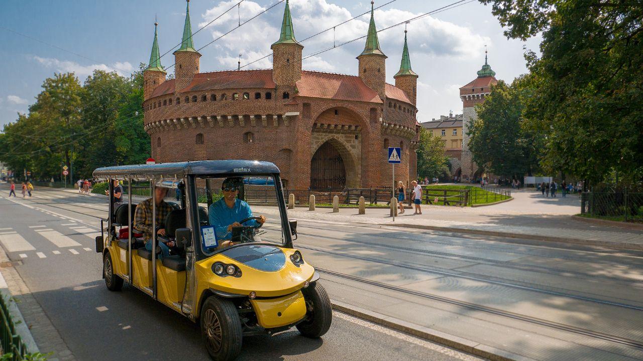 Touristes profitant de la ville de Cracovie à bord d'un confortable melex.
